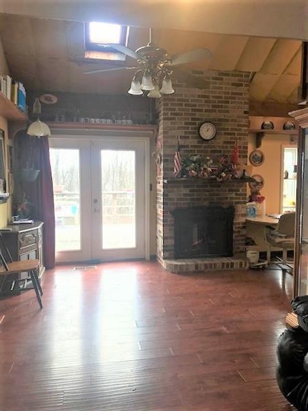 living room with brick wall, french doors, ceiling fan, dark hardwood / wood-style flooring, and a fireplace