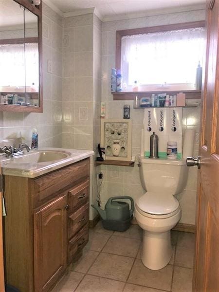 bathroom with tile walls, tile flooring, toilet, and vanity