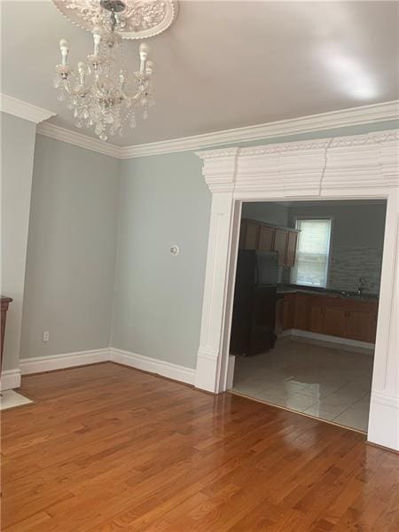 spare room featuring a notable chandelier, tile floors, and crown molding