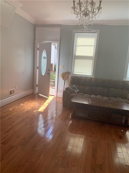 entryway with plenty of natural light, hardwood / wood-style floors, ornamental molding, and a chandelier