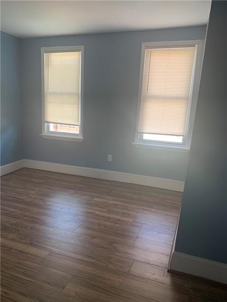 empty room with plenty of natural light and dark hardwood / wood-style floors