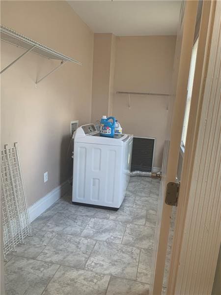 clothes washing area with washer / clothes dryer and light tile floors