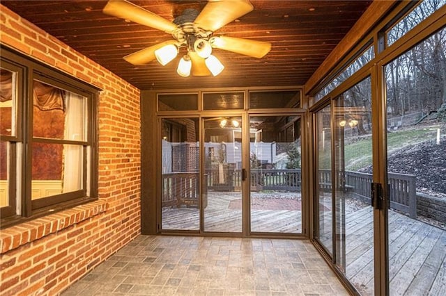 unfurnished sunroom featuring plenty of natural light, wooden ceiling, and ceiling fan