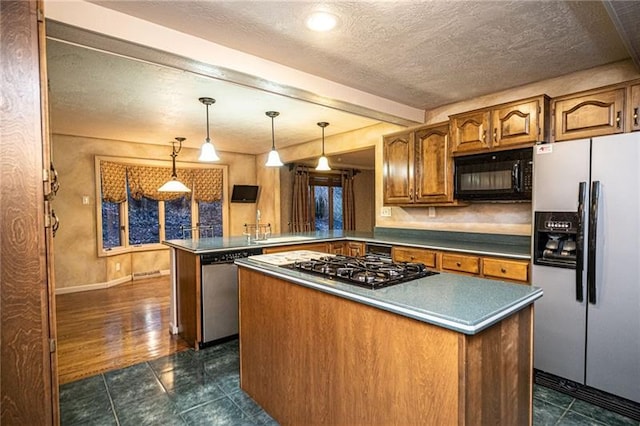 kitchen with a kitchen island, decorative light fixtures, a textured ceiling, kitchen peninsula, and appliances with stainless steel finishes