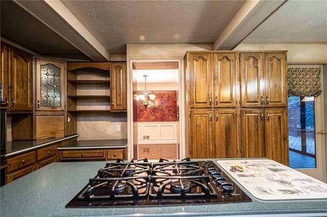 kitchen featuring black gas stovetop, a textured ceiling, and an inviting chandelier