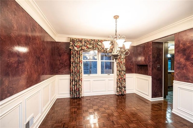 unfurnished dining area with crown molding, dark parquet flooring, and a chandelier