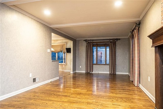 unfurnished room with beam ceiling, ornamental molding, and wood-type flooring