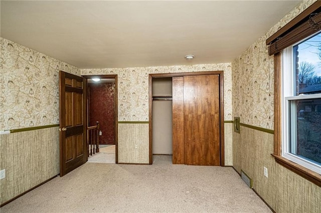 interior space with a closet, light colored carpet, and multiple windows