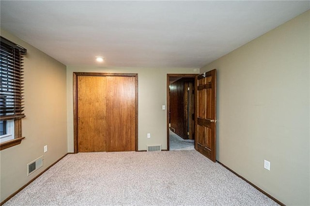 unfurnished bedroom with light carpet and a closet