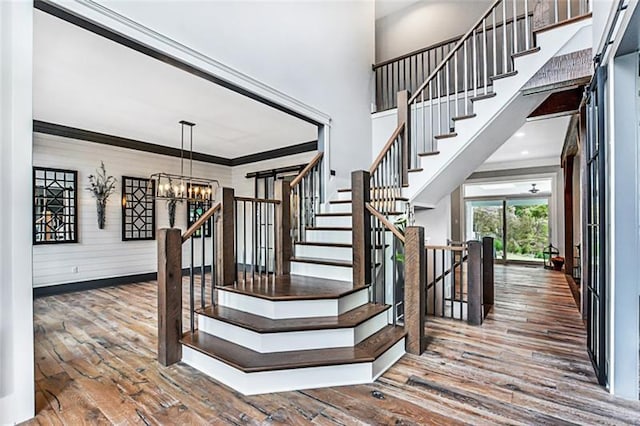 staircase featuring a chandelier, dark hardwood / wood-style floors, and ornamental molding