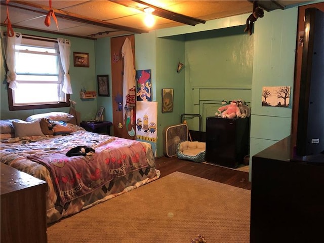 bedroom with ceiling fan, dark wood-type flooring, and beamed ceiling