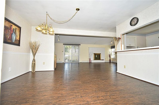 unfurnished living room featuring dark hardwood / wood-style flooring, an inviting chandelier, a baseboard radiator, and beamed ceiling