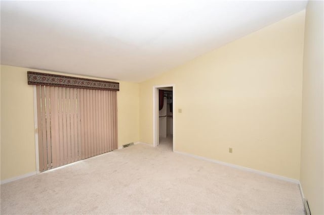 carpeted empty room featuring vaulted ceiling