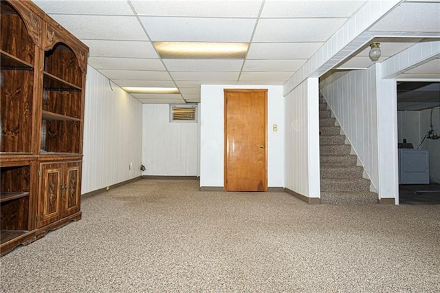 basement with a paneled ceiling, washer / dryer, and light colored carpet