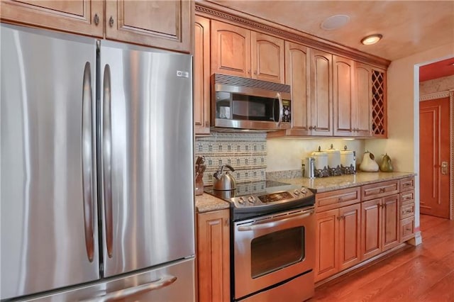 kitchen featuring stainless steel appliances, light wood-type flooring, and light stone counters