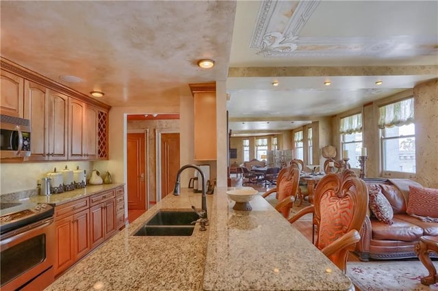 kitchen featuring a kitchen bar, stove, sink, and light stone countertops