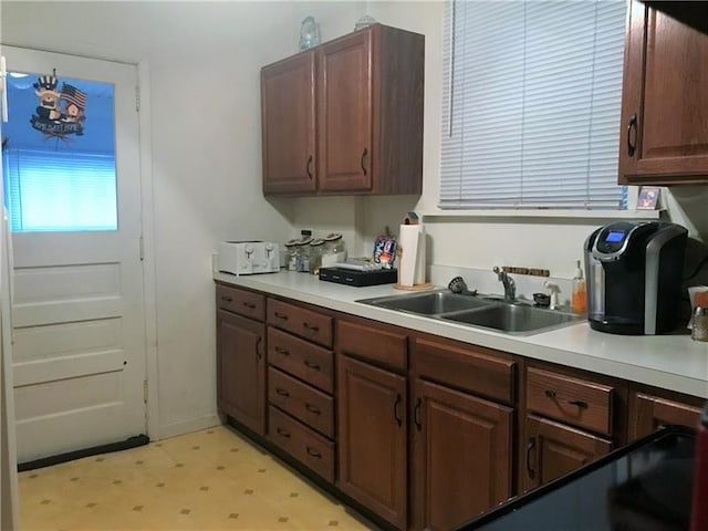 kitchen with sink, dark brown cabinets, and light tile floors