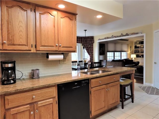 kitchen featuring tasteful backsplash, light tile floors, dishwasher, sink, and light stone countertops