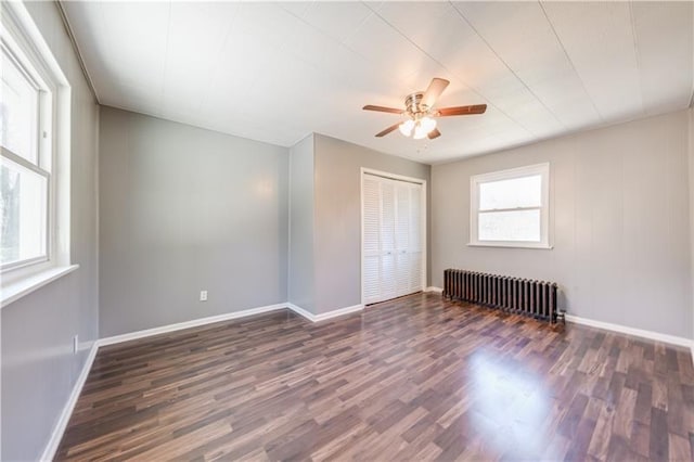 unfurnished bedroom featuring multiple windows, dark hardwood / wood-style floors, and radiator