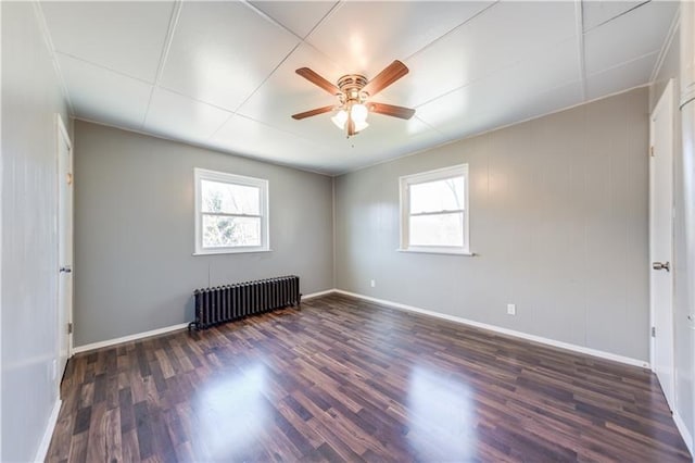 spare room with ceiling fan, dark hardwood / wood-style floors, and radiator heating unit