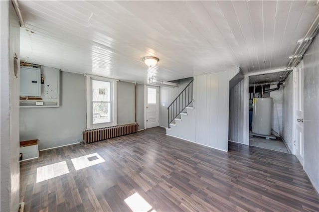 spare room with water heater, dark hardwood / wood-style floors, and radiator