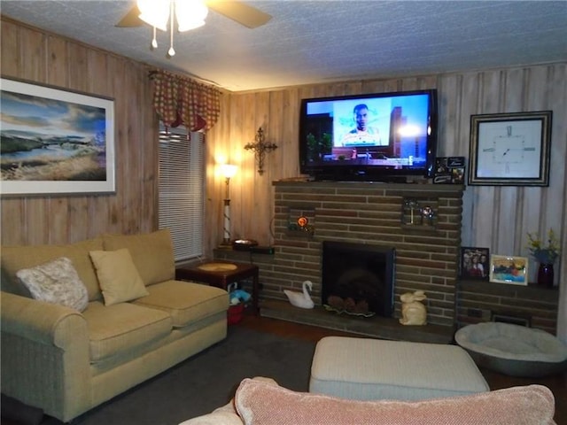 living room featuring wood walls, ceiling fan, and a fireplace