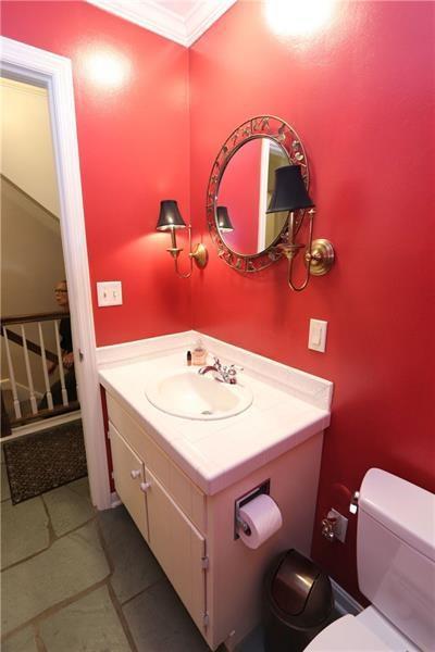 bathroom with tile floors, crown molding, vanity with extensive cabinet space, and toilet