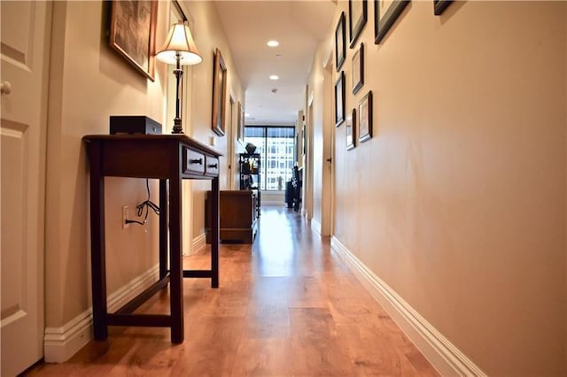 hallway featuring floor to ceiling windows and light hardwood / wood-style floors