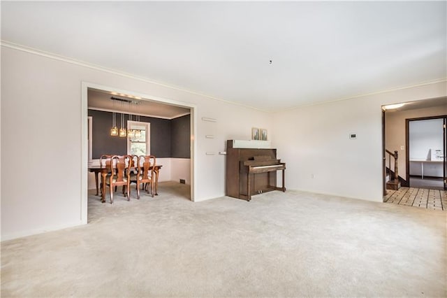 carpeted spare room with ornamental molding and a chandelier