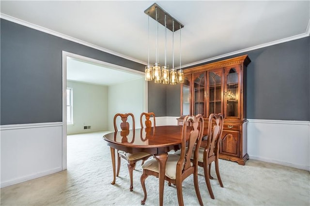 dining room with a notable chandelier, ornamental molding, and light carpet