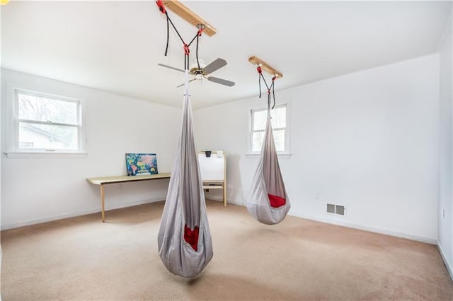 interior space with ceiling fan, light carpet, and plenty of natural light