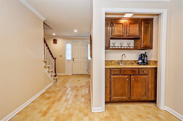 bar with ornamental molding, light stone counters, and sink