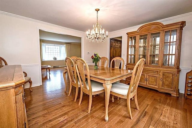 dining space with crown molding, dark wood-type flooring, and an inviting chandelier