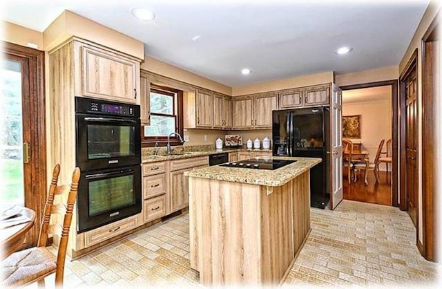 kitchen with a center island, plenty of natural light, light stone countertops, and black appliances