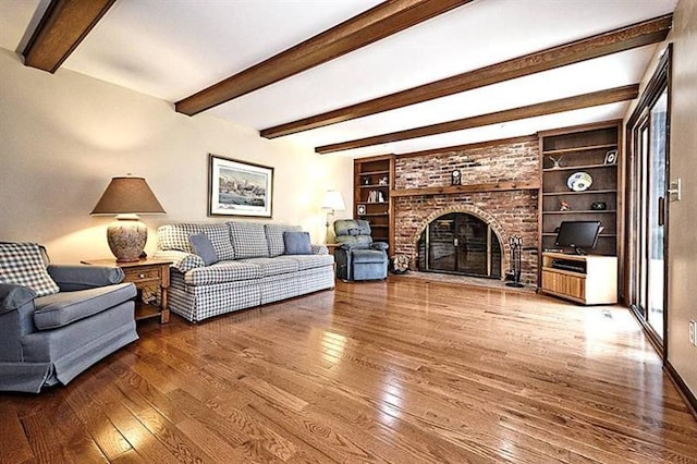 living room with beamed ceiling, built in features, dark hardwood / wood-style flooring, and a fireplace