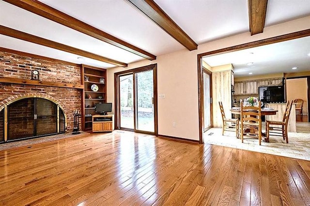 unfurnished living room featuring brick wall, a brick fireplace, built in shelves, and light wood-type flooring