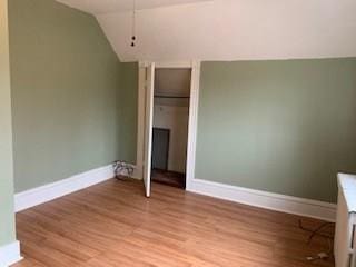 unfurnished bedroom featuring vaulted ceiling and light hardwood / wood-style flooring