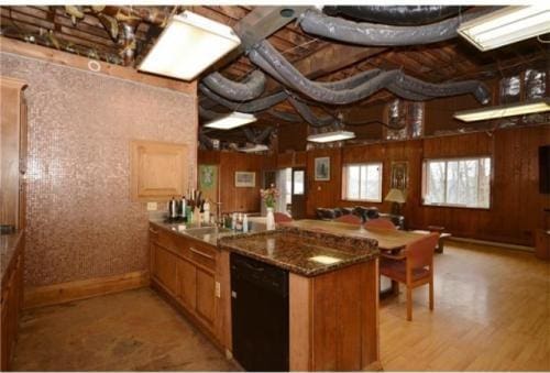 kitchen with black dishwasher, light hardwood / wood-style floors, sink, and dark stone counters