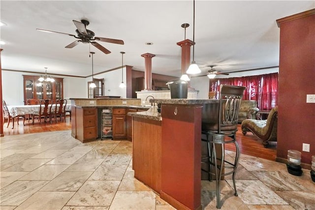 kitchen with ornamental molding, a breakfast bar, and ceiling fan with notable chandelier