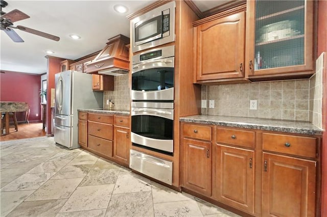 kitchen with custom range hood, ceiling fan, backsplash, and stainless steel appliances