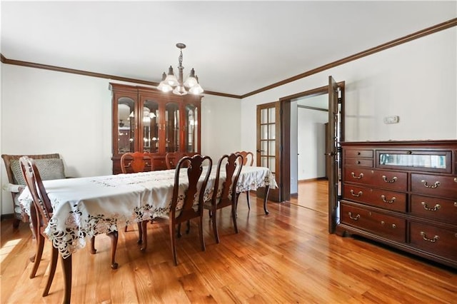 dining room featuring an inviting chandelier, ornamental molding, and light hardwood / wood-style flooring