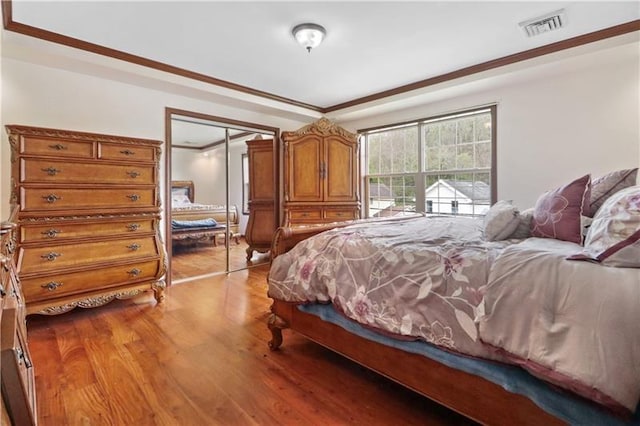 bedroom featuring light hardwood / wood-style floors, ornamental molding, and a closet