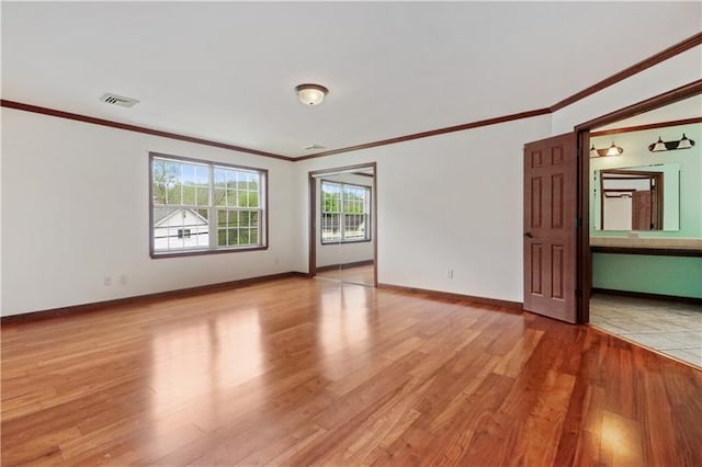 empty room featuring ornamental molding and light hardwood / wood-style flooring