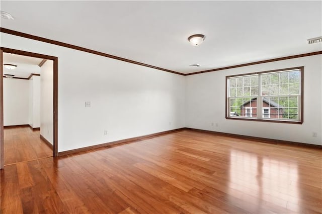 empty room featuring ornamental molding and light wood-type flooring