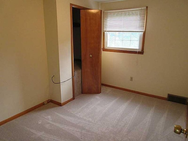 unfurnished bedroom with a closet and light colored carpet