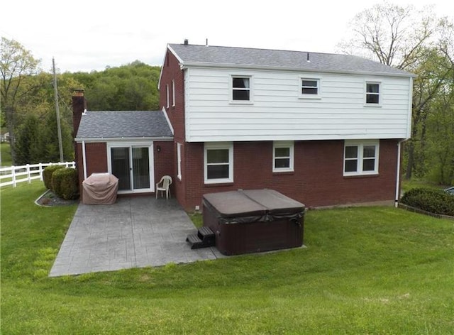 rear view of house with a yard, a patio, and a hot tub