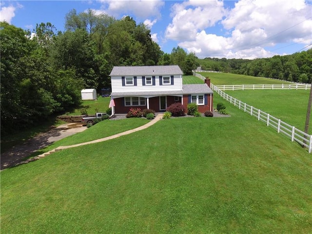 view of front of property featuring a rural view, a front yard, and a shed