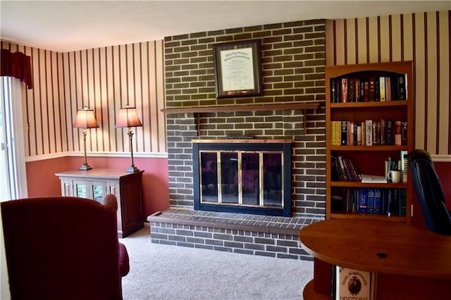 carpeted living room with brick wall and a brick fireplace