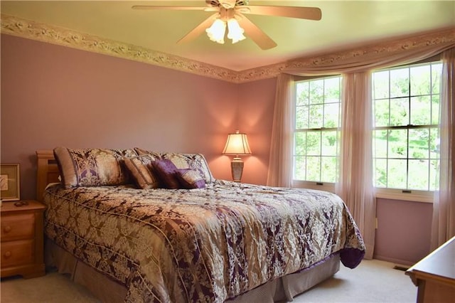 carpeted bedroom with ceiling fan and multiple windows