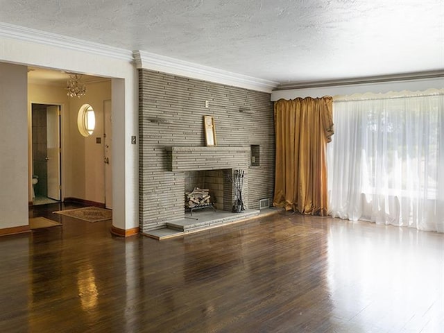 unfurnished living room featuring a notable chandelier, a stone fireplace, dark wood-type flooring, and a textured ceiling